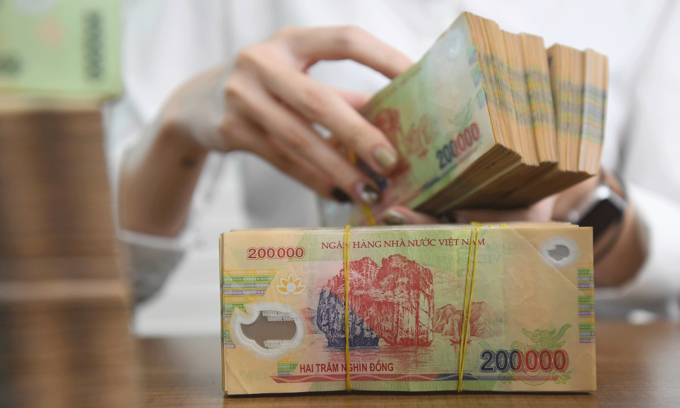 Сотрудник пересчитывает вьетнамские банкноты в банке в Ханое.